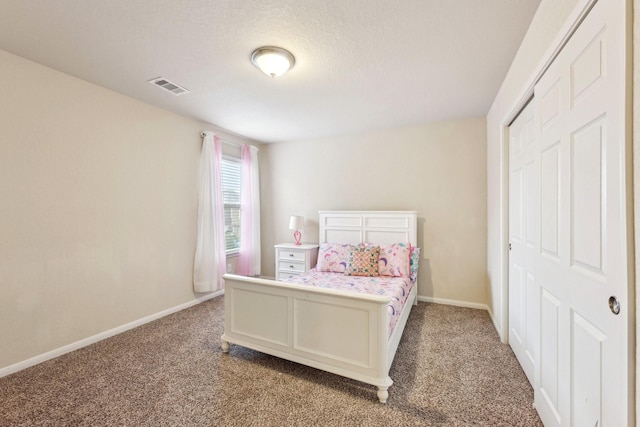 carpeted bedroom with a textured ceiling and a closet