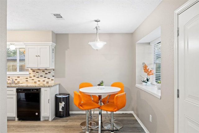 kitchen with white cabinets, pendant lighting, black dishwasher, and decorative backsplash