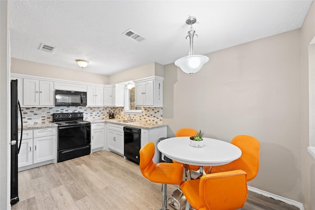 kitchen with black appliances, white cabinets, hanging light fixtures, decorative backsplash, and light wood-type flooring