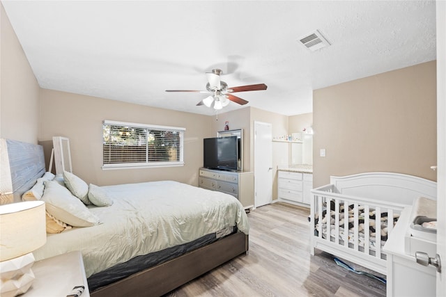 bedroom featuring ceiling fan, light hardwood / wood-style floors, and connected bathroom