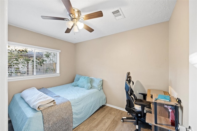 bedroom featuring ceiling fan, light hardwood / wood-style floors, and a textured ceiling