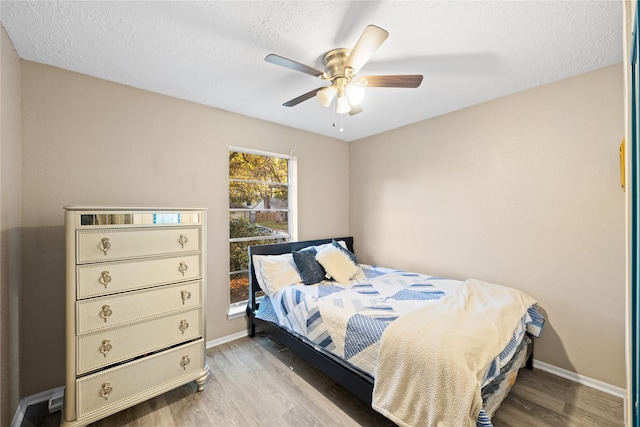 bedroom with ceiling fan, wood-type flooring, and a textured ceiling