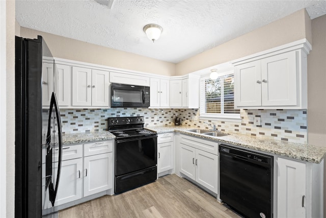 kitchen featuring backsplash, sink, black appliances, white cabinets, and light hardwood / wood-style floors