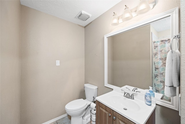 bathroom featuring a textured ceiling, vanity, and toilet