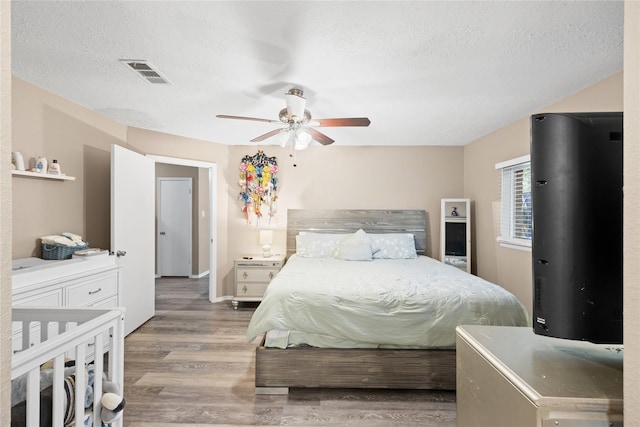 bedroom featuring a textured ceiling, light hardwood / wood-style flooring, and ceiling fan