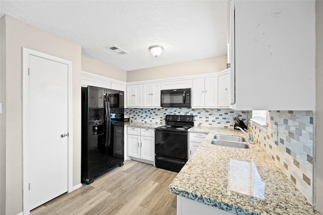 kitchen with black appliances, light hardwood / wood-style flooring, tasteful backsplash, light stone counters, and white cabinetry