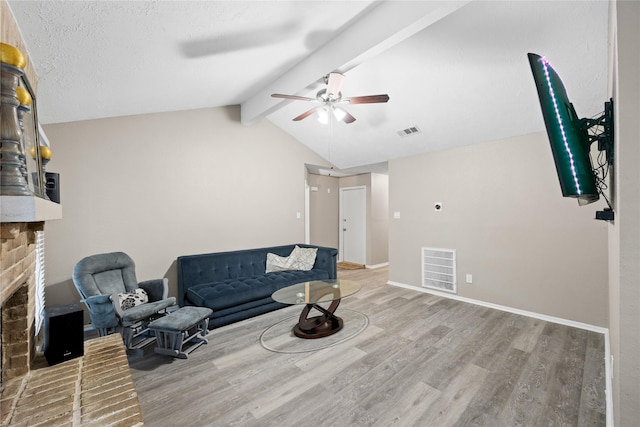 living room featuring lofted ceiling with beams, ceiling fan, light wood-type flooring, and a brick fireplace