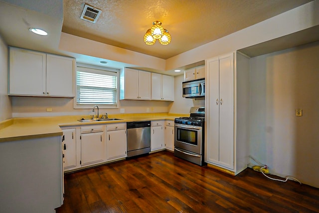 kitchen featuring sink, white cabinets, appliances with stainless steel finishes, a textured ceiling, and dark hardwood / wood-style flooring