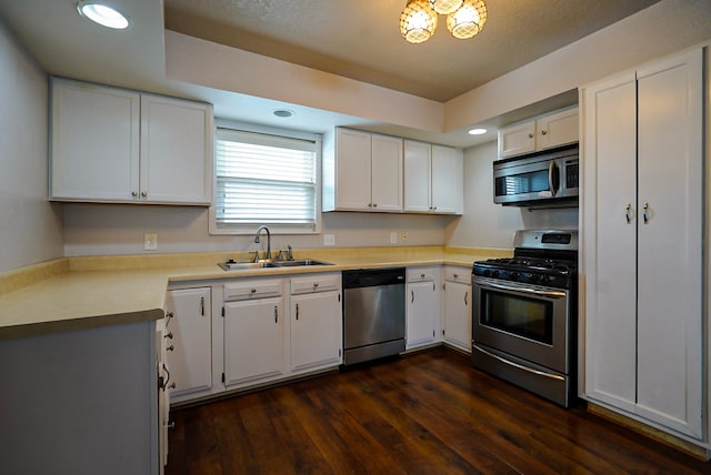 kitchen with appliances with stainless steel finishes, white cabinets, sink, and dark hardwood / wood-style flooring