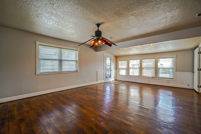 empty room with a textured ceiling, dark wood-type flooring, and ceiling fan