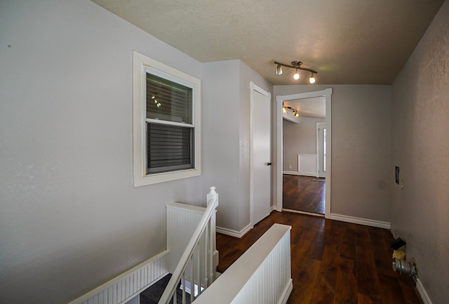 corridor with dark hardwood / wood-style floors and a textured ceiling