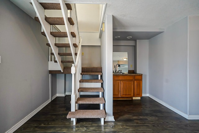 stairs with sink, hardwood / wood-style flooring, and a textured ceiling