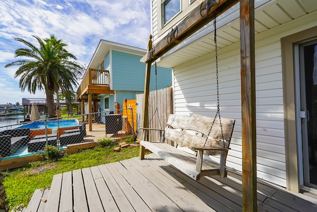 wooden deck featuring a water view and a pool