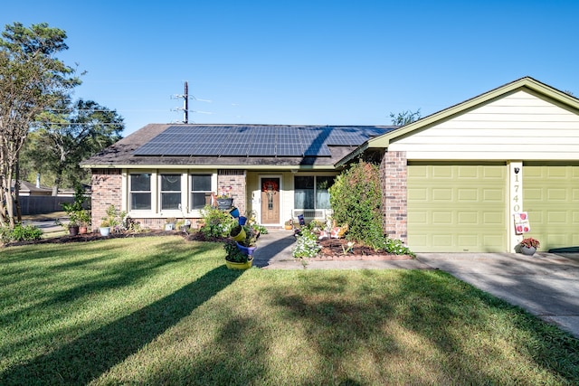 single story home with solar panels, a front yard, and a garage