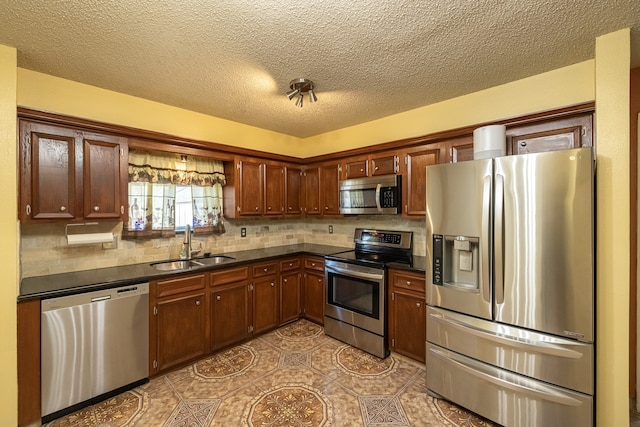 kitchen featuring a textured ceiling, tasteful backsplash, stainless steel appliances, and sink