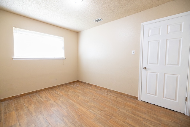 unfurnished room featuring a textured ceiling and light hardwood / wood-style flooring