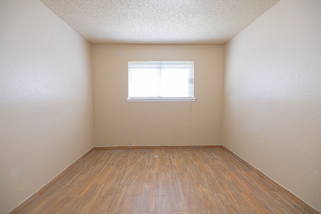 empty room featuring light hardwood / wood-style flooring and a textured ceiling