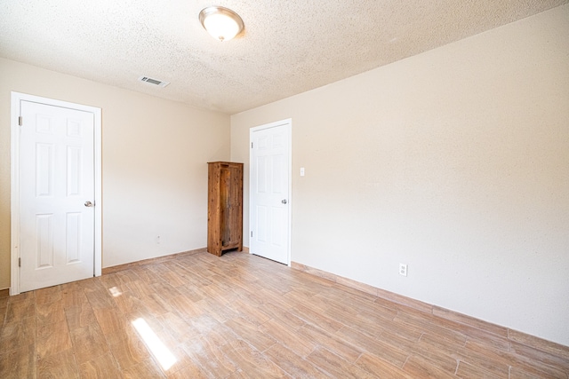 empty room featuring light hardwood / wood-style floors and a textured ceiling