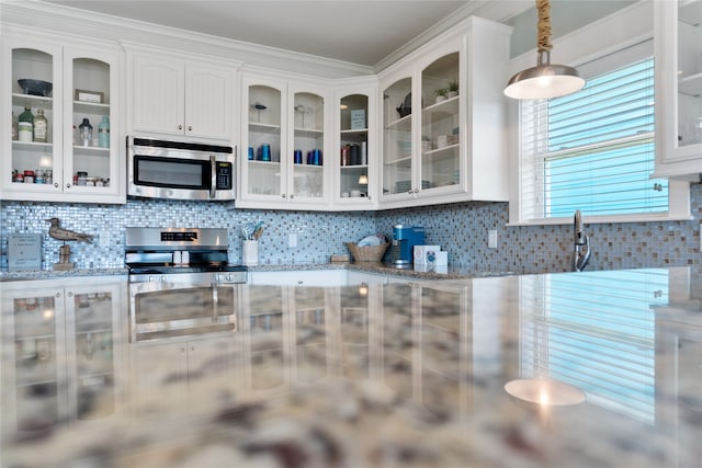 kitchen with hanging light fixtures, stainless steel appliances, light stone countertops, white cabinetry, and tasteful backsplash