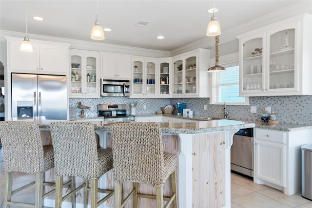 kitchen with light tile patterned flooring, a sink, stainless steel appliances, white cabinets, and a center island