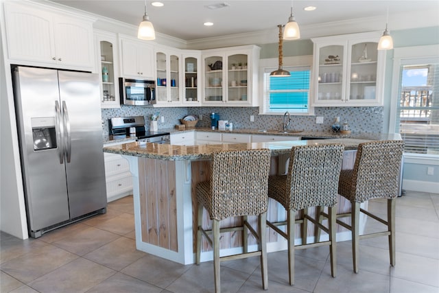 kitchen featuring ornamental molding, a center island, appliances with stainless steel finishes, and white cabinetry