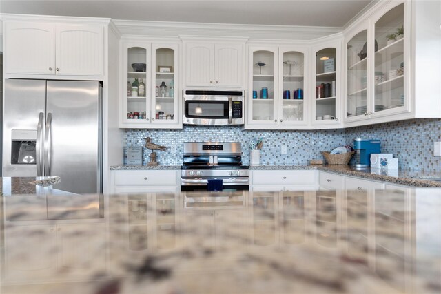 kitchen with white cabinetry, light stone counters, stainless steel appliances, and tasteful backsplash