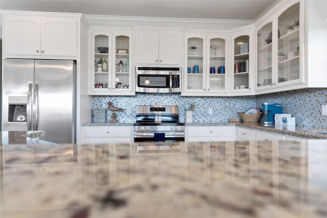 kitchen featuring white cabinetry, decorative backsplash, glass insert cabinets, and stainless steel appliances