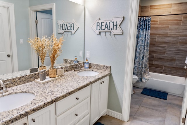 bathroom featuring double vanity, tile patterned flooring, toilet, and a sink