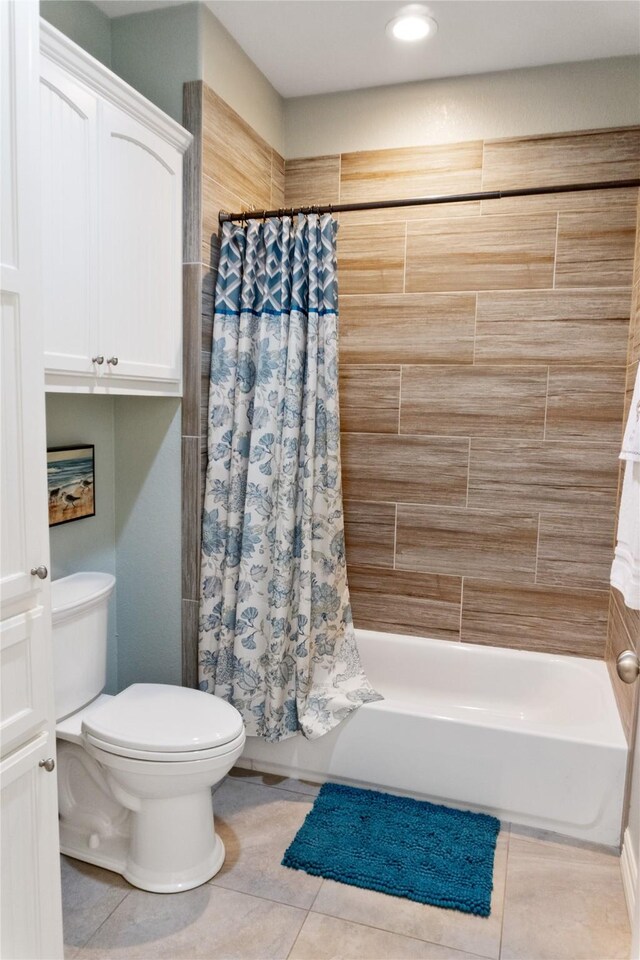 bathroom featuring shower / bath combo with shower curtain, toilet, and tile patterned floors