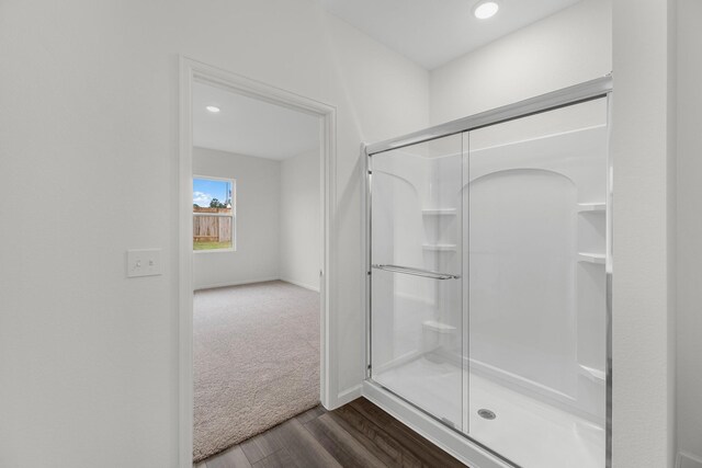 bathroom with a shower stall, baseboards, wood finished floors, and recessed lighting