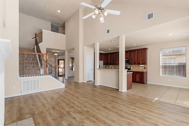 unfurnished living room featuring light wood-type flooring, high vaulted ceiling, and ceiling fan