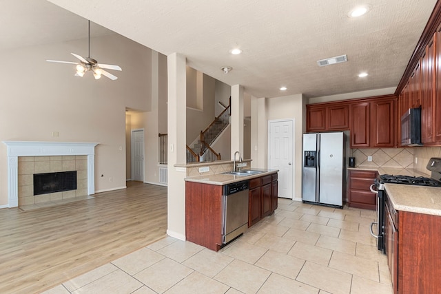 kitchen with ceiling fan, a textured ceiling, sink, light hardwood / wood-style floors, and stainless steel appliances