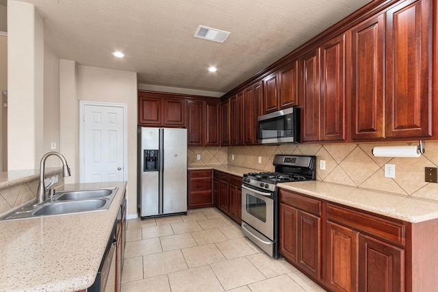 kitchen featuring stainless steel appliances, sink, light tile patterned flooring, light stone counters, and tasteful backsplash