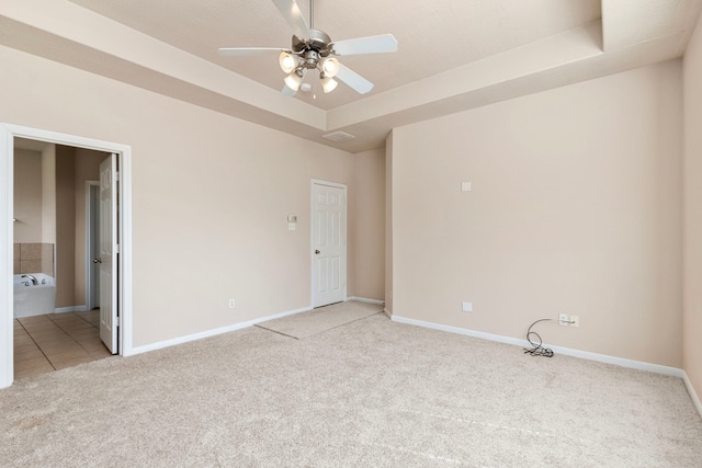 carpeted spare room with ceiling fan and a raised ceiling