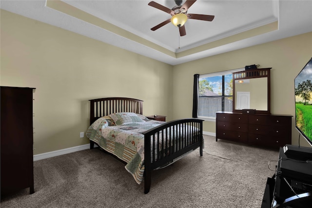 bedroom featuring ornamental molding, a tray ceiling, carpet floors, and ceiling fan