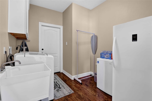 washroom featuring washing machine and dryer, sink, dark hardwood / wood-style floors, and cabinets