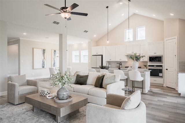 living room featuring a wealth of natural light, light hardwood / wood-style flooring, high vaulted ceiling, and ceiling fan