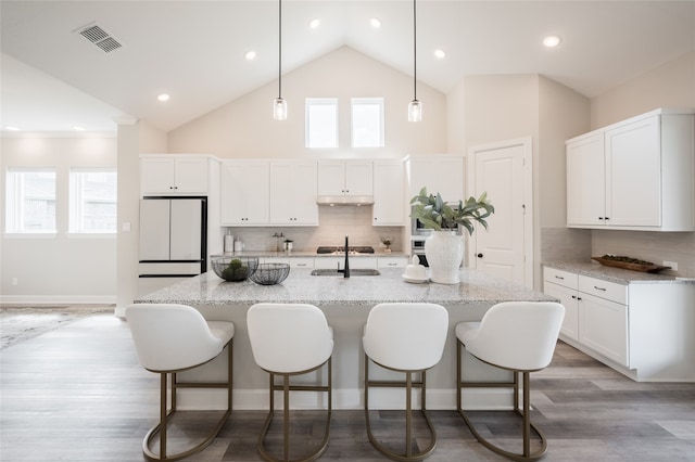 kitchen featuring backsplash, white cabinetry, a healthy amount of sunlight, and white refrigerator