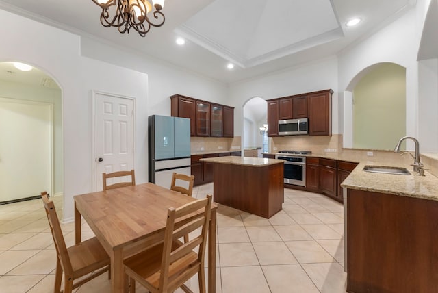 kitchen with kitchen peninsula, ornamental molding, light tile patterned flooring, sink, and stainless steel appliances