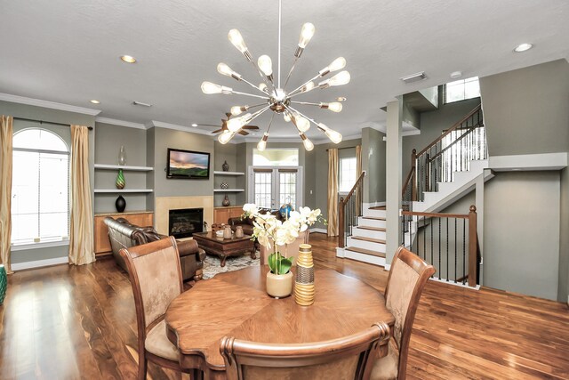 dining room featuring crown molding, hardwood / wood-style flooring, built in features, a textured ceiling, and a chandelier