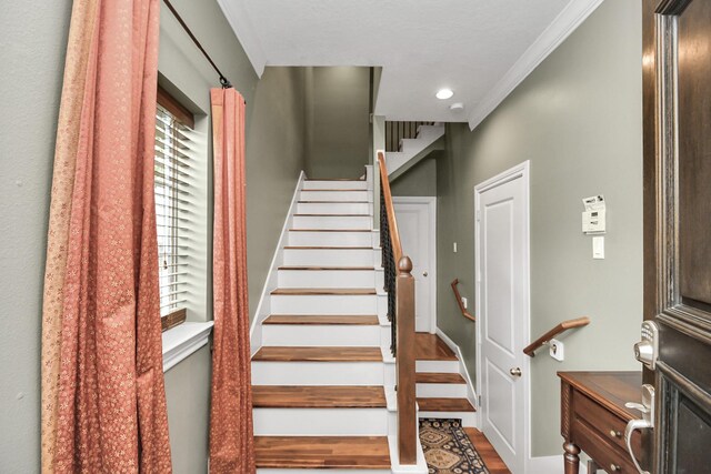 stairs featuring crown molding, hardwood / wood-style floors, and a wealth of natural light