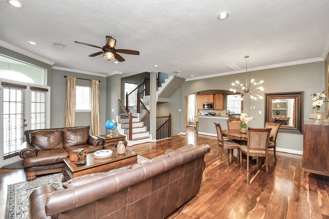 living room featuring hardwood / wood-style flooring, ceiling fan with notable chandelier, ornamental molding, and a textured ceiling