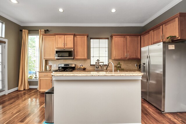 kitchen featuring stainless steel appliances, tasteful backsplash, a kitchen island, and ornamental molding