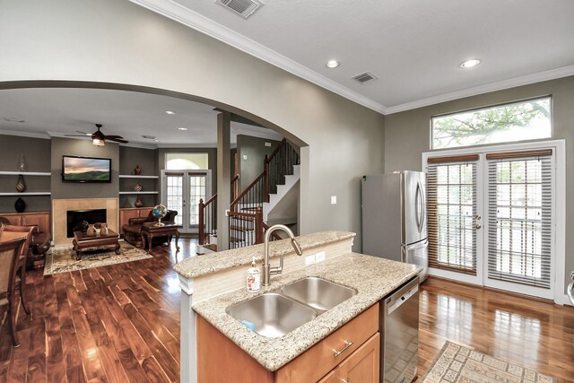 kitchen featuring sink, appliances with stainless steel finishes, light stone counters, a center island with sink, and dark hardwood / wood-style flooring