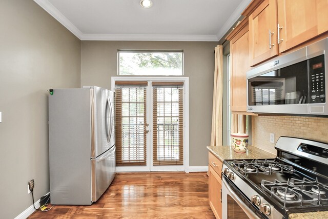 kitchen featuring appliances with stainless steel finishes, tasteful backsplash, ornamental molding, light hardwood / wood-style floors, and french doors