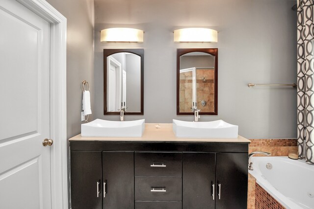 bathroom with vanity and tiled tub