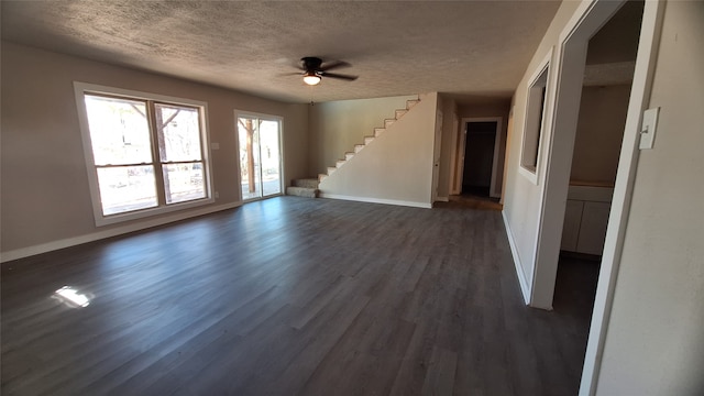 1284 Beaver Lake Dr, Caldwell, TX 77836 - unfurnished living room with a textured ceiling, ceiling fan, baseboards, dark wood-type flooring, and stairs