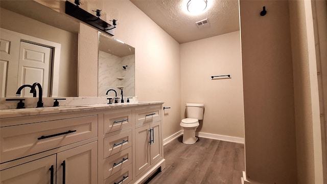 bathroom with vanity, toilet, wood-type flooring, and a textured ceiling