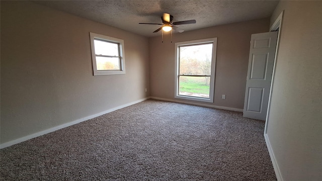 carpeted spare room featuring a textured ceiling and ceiling fan