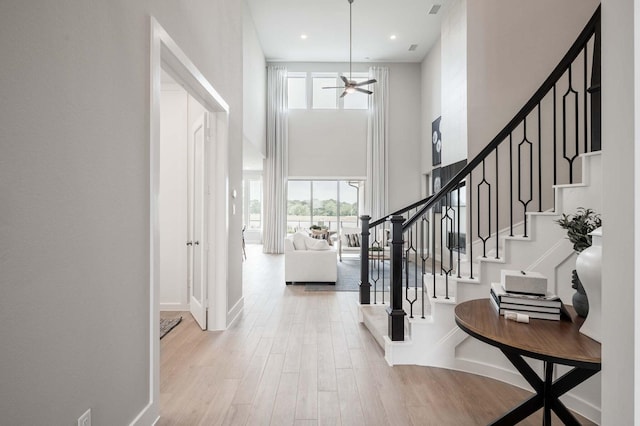 foyer featuring a high ceiling, ceiling fan, and light hardwood / wood-style flooring